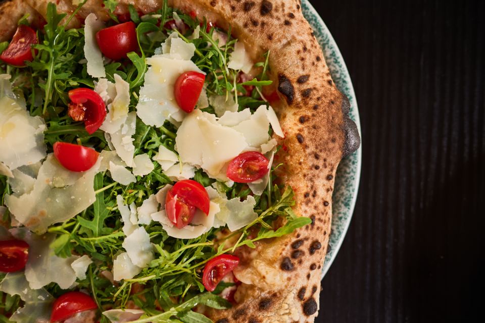 Neapolitan pizza with rucola, parmesan and cherry tomatoes