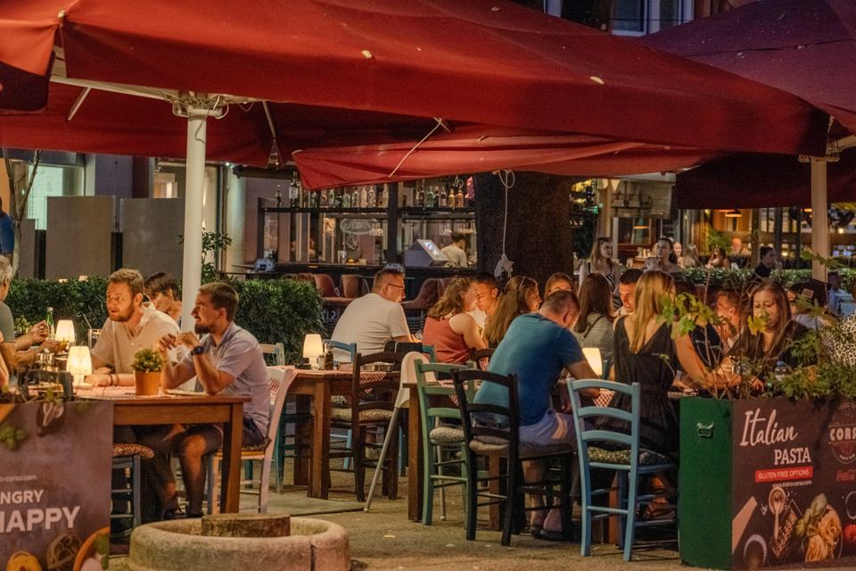 Evening on the terrace of Bistro Corso under red umbrellas